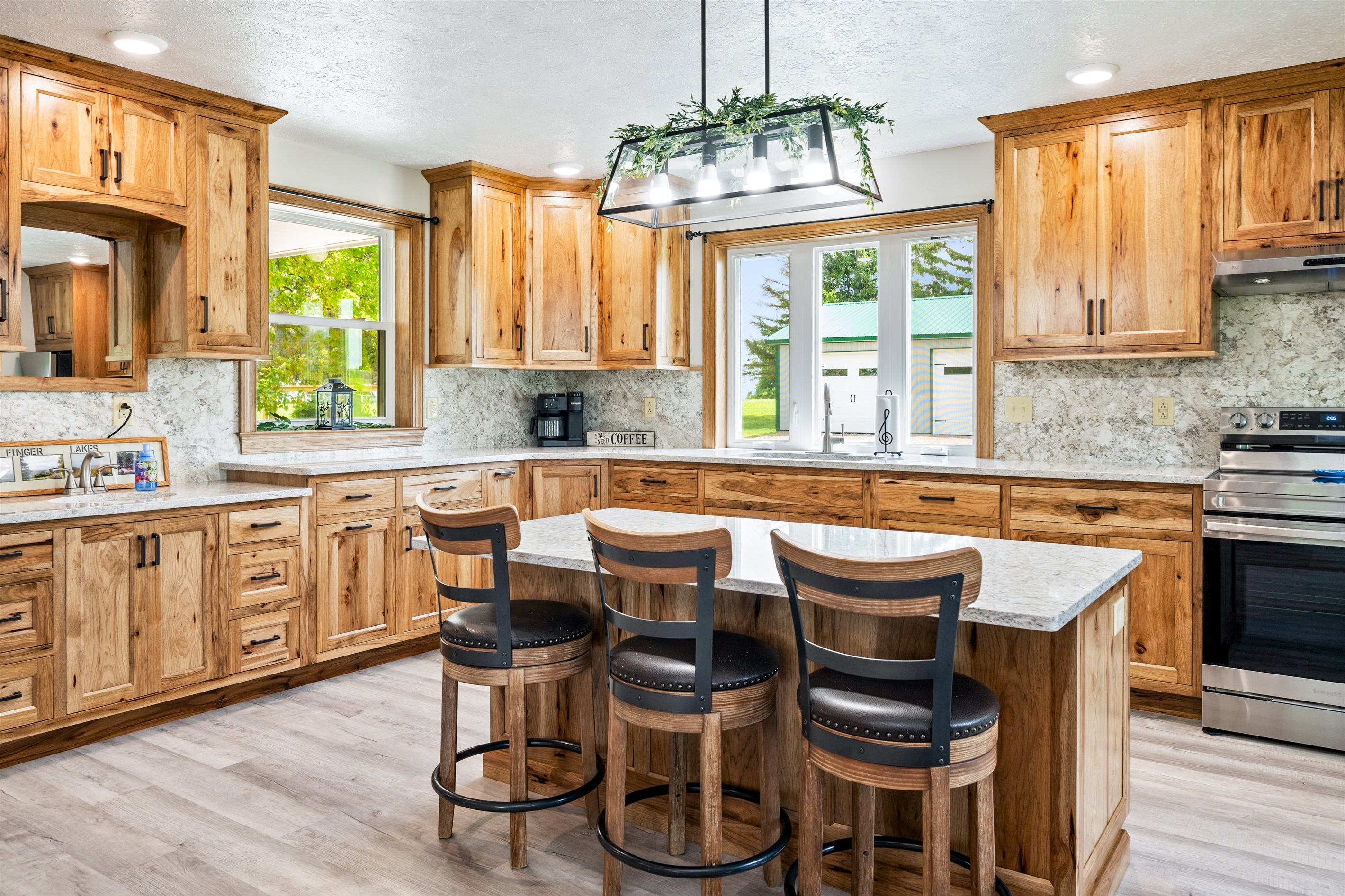 Cook in style in this fully equipped kitchen with natural wood cabinetry, granite countertops, stainless steel appliances, and a large center island with seating.