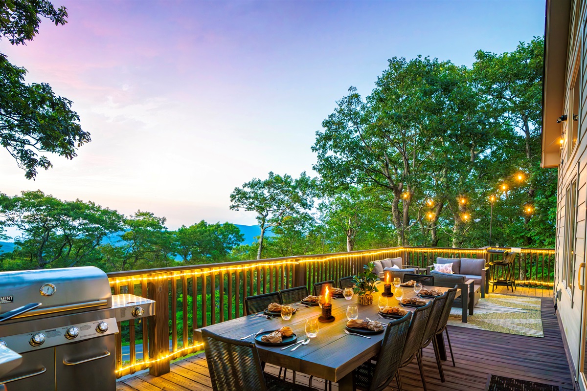 Twilight on the deck — mountains fading in the distance, wine glasses catching the glow of string lights, dinner sizzling on the grill. This is what gathering should feel like