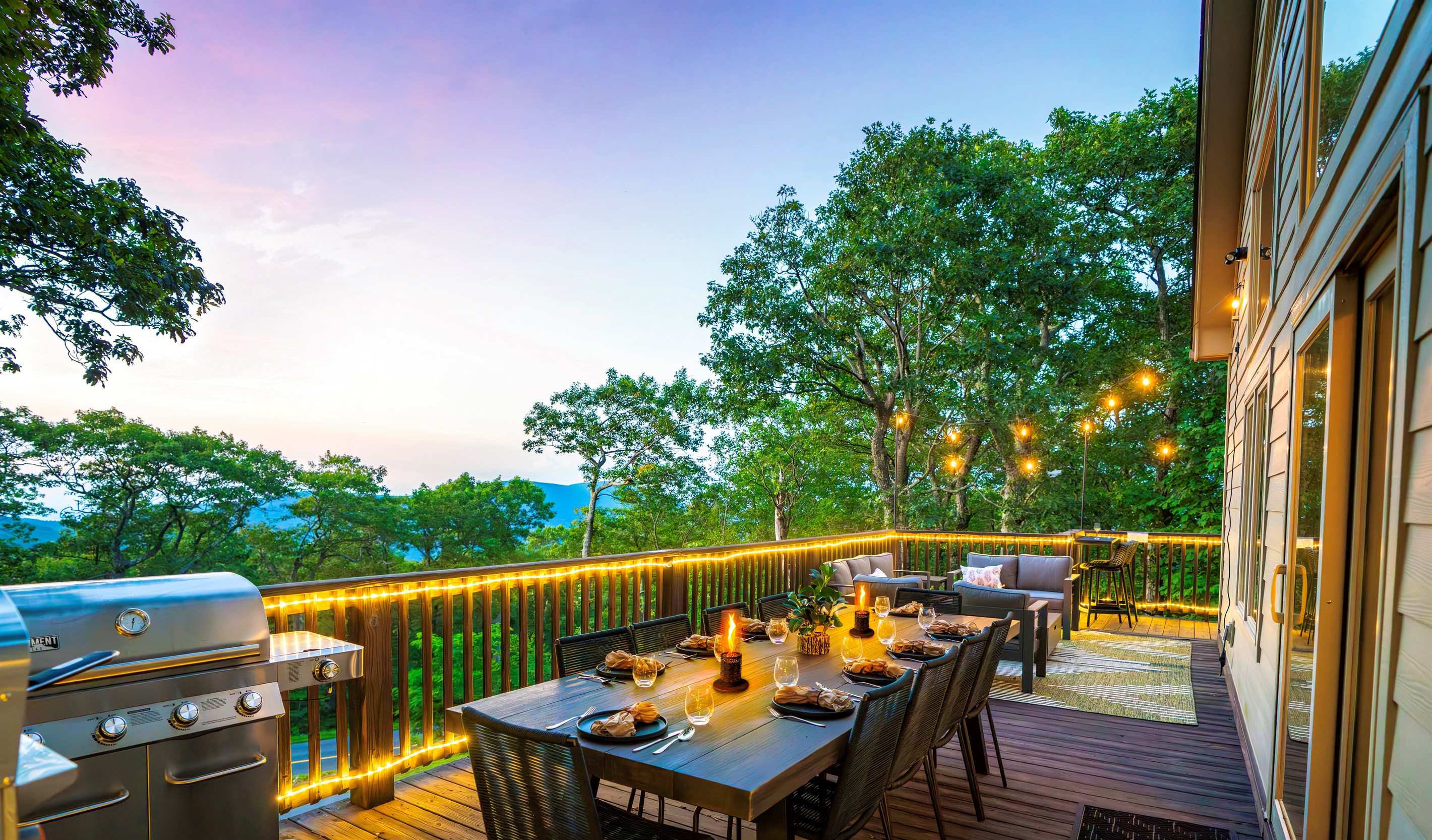 Twilight on the deck — mountains fading in the distance, wine glasses catching the glow of string lights, dinner sizzling on the grill. This is what gathering should feel like
