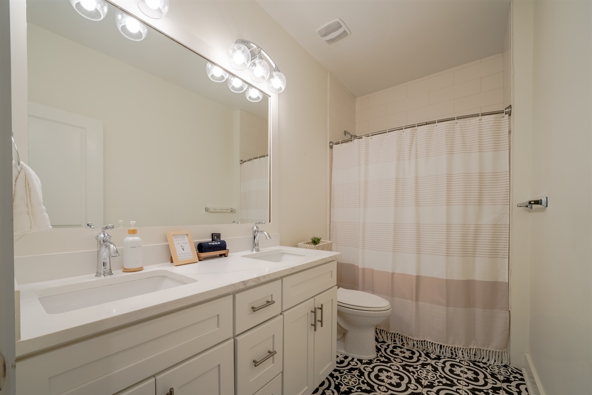 Full bathroom with double vanity and shower-tub combo