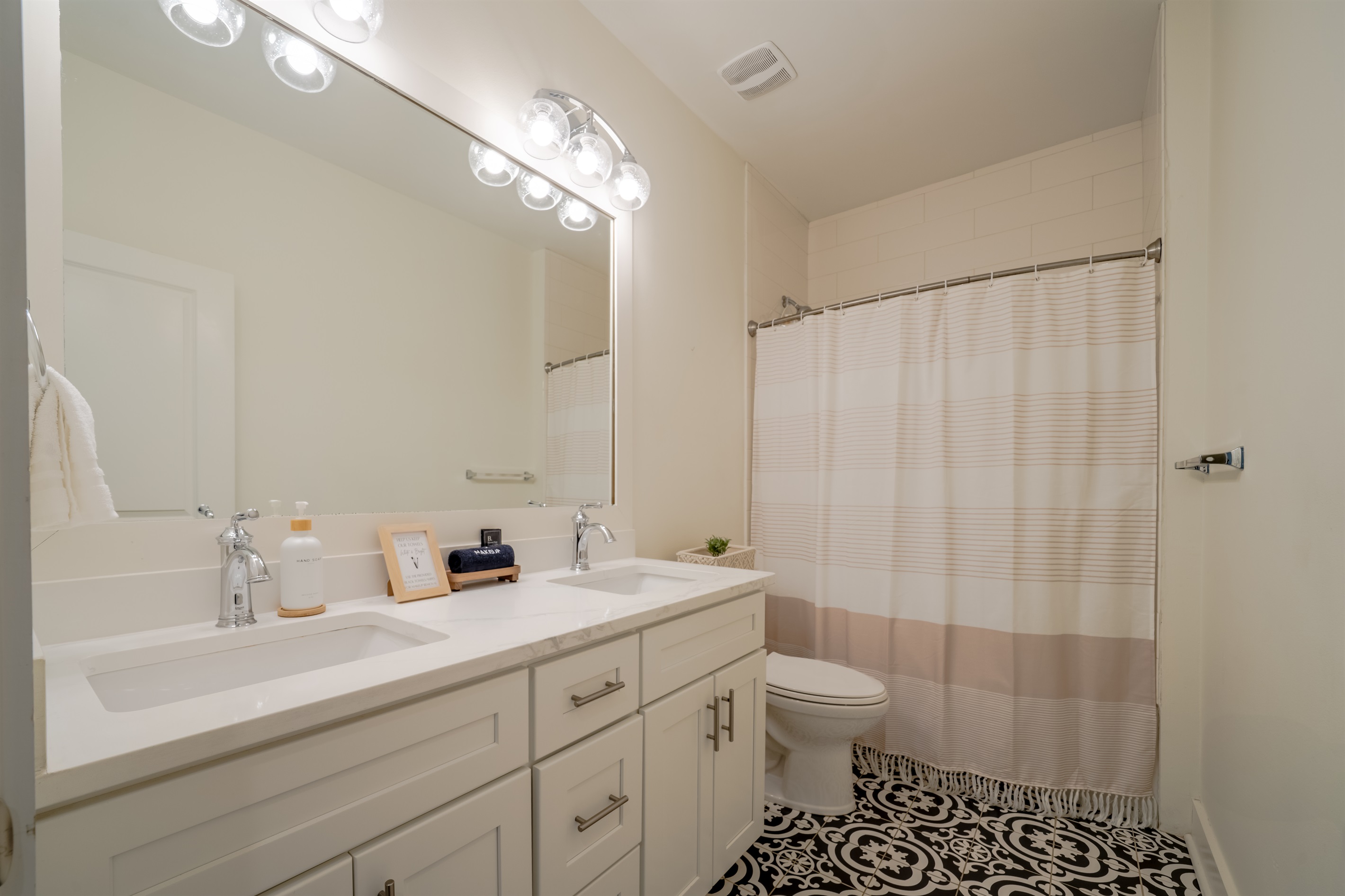 Full bathroom with double vanity and shower-tub combo