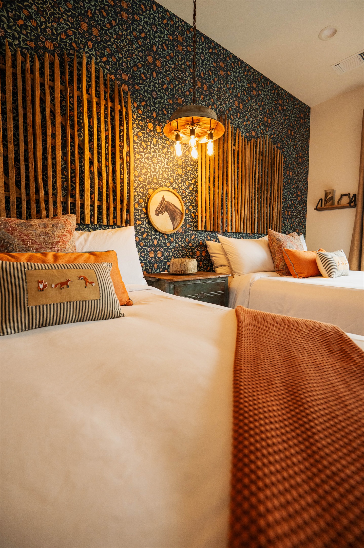 Pendant lighting and the bamboo feature wall at the Corral Suite — layered modern Western design over two queen beds.