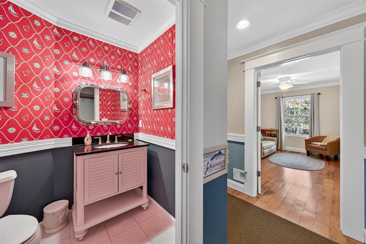 Bright half bath with bold wallpaper and coastal charm, for your convenience..
