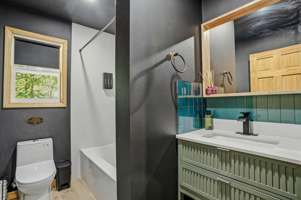 Bathroom with tub/shower combo, dark tile surround, and modern fixtures