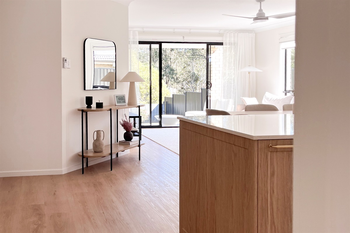 From the kitchen area, the view carries through the lounge to the patio and leafy backyard beyond.
