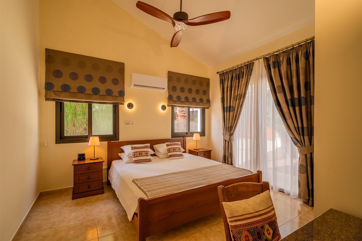First king bedroom with direct patio access. King size bed, ceiling fan, dedicated AC/heating unit, vanity, large built-in wardrobes, bluetooth speaker/alarm clock.