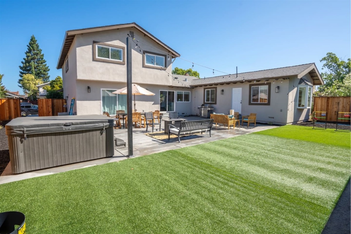 Backyard with hot tub, outdoor dining and seating with fire pit.