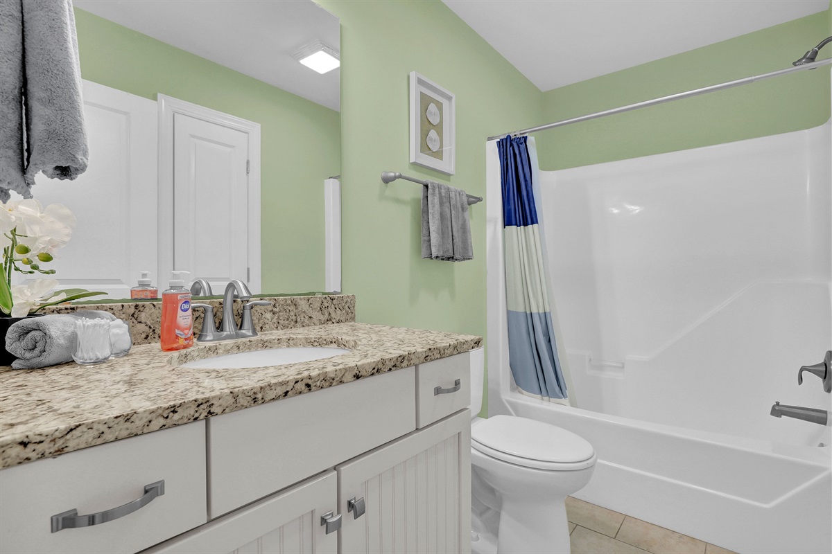 Clean, modern full bathroom with tub/shower combo and granite vanity.