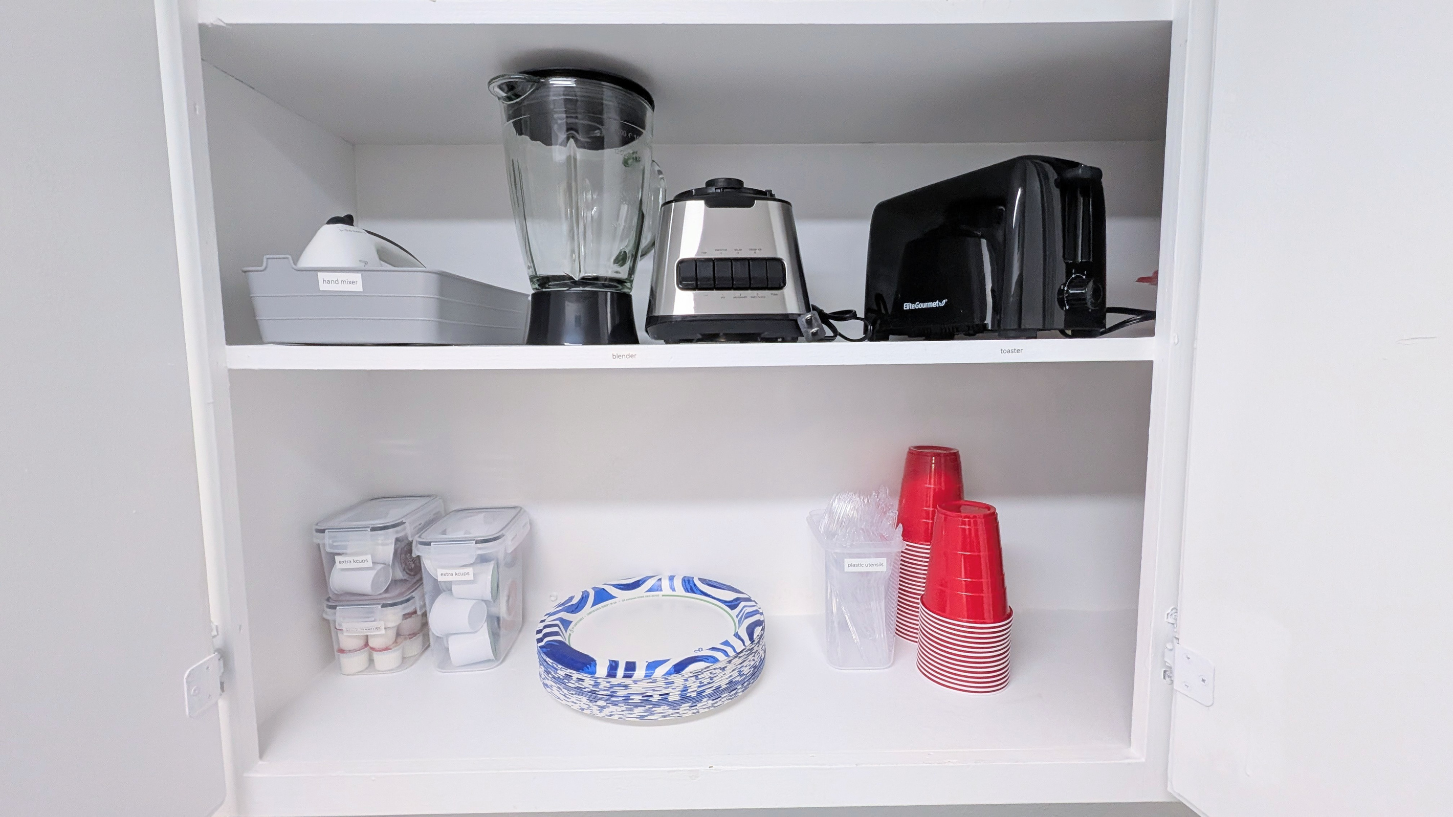 Small appliances, including a hand mixer, blender, and toaster, are provided, along with extra coffee supplies and disposable plates, utensils, and cups.