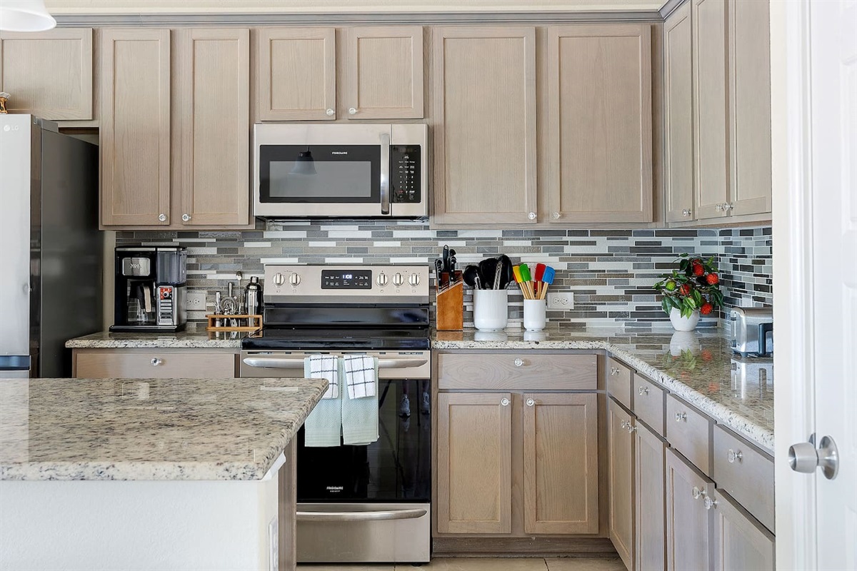 Step into a modern kitchen equipped with stainless steel appliances, a sleek microwave, and ample counter space featuring stylish granite countertops.