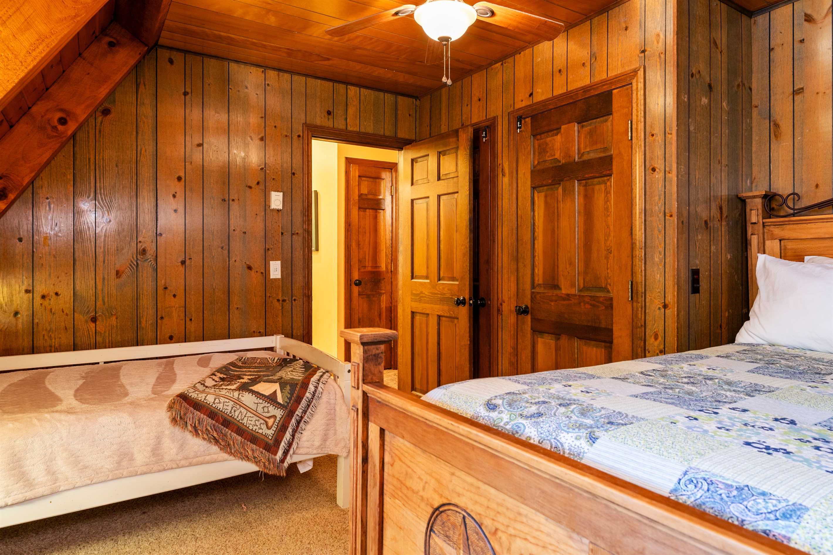 Bedroom #2 Charming log cabin bedroom with a queen bed and twin bed, natural wood beams, and bright windows showcasing forest views.