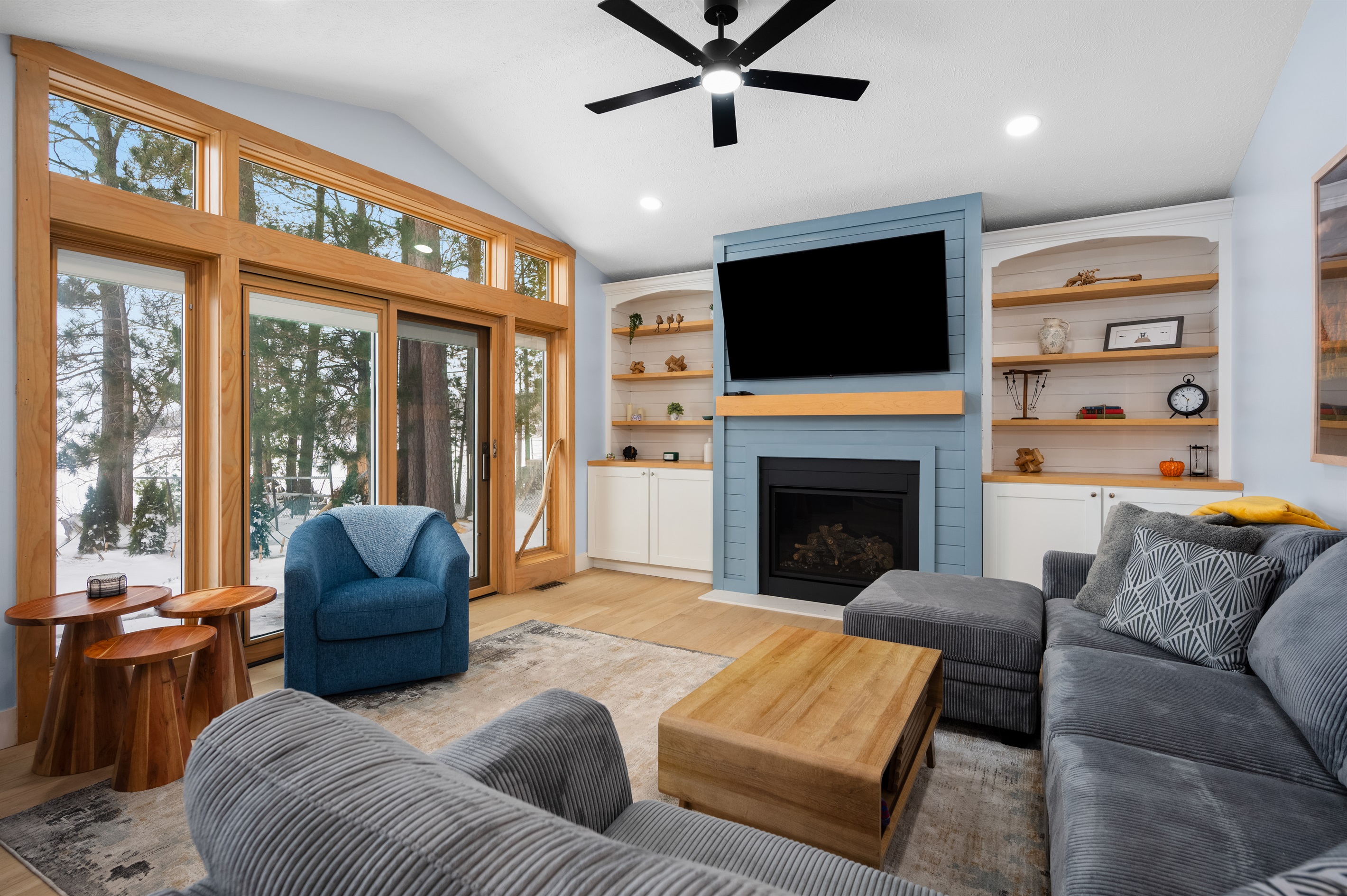 Living room with cozy couch, gas fireplace and endless views of Long Lake.