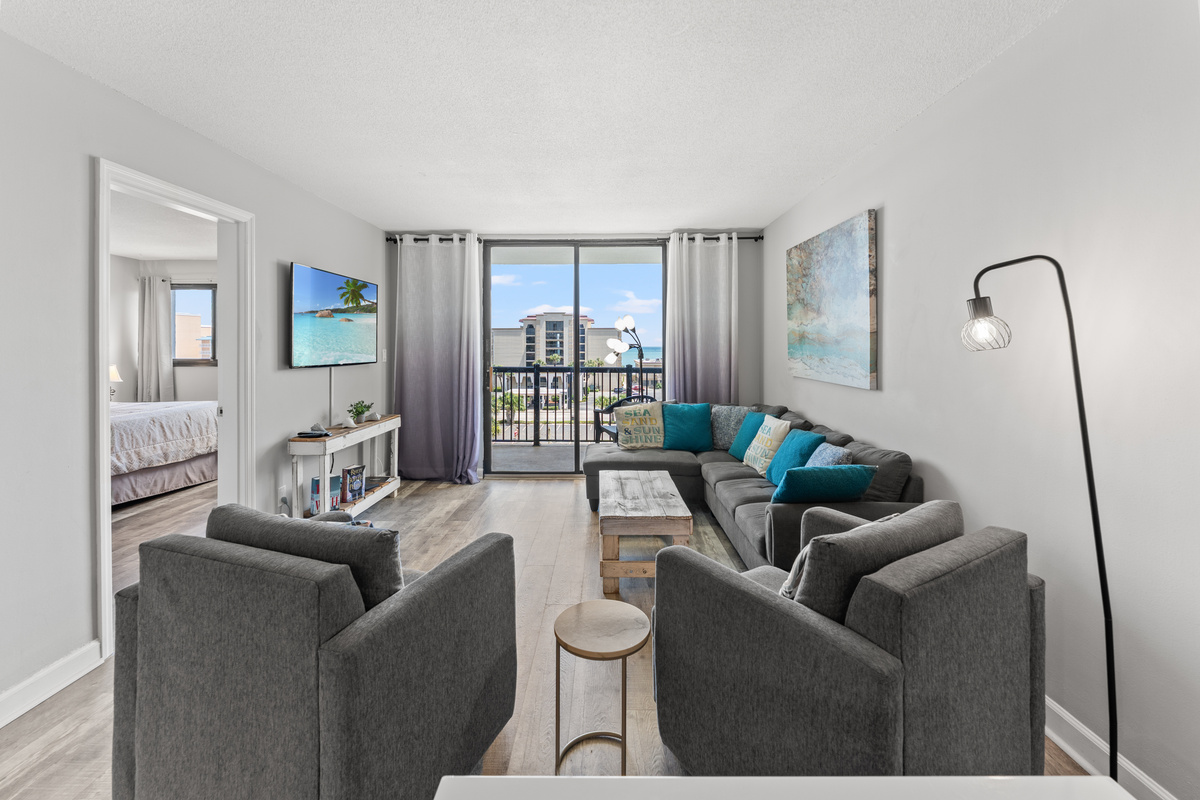 Comfy living room area with large TV and balcony access
