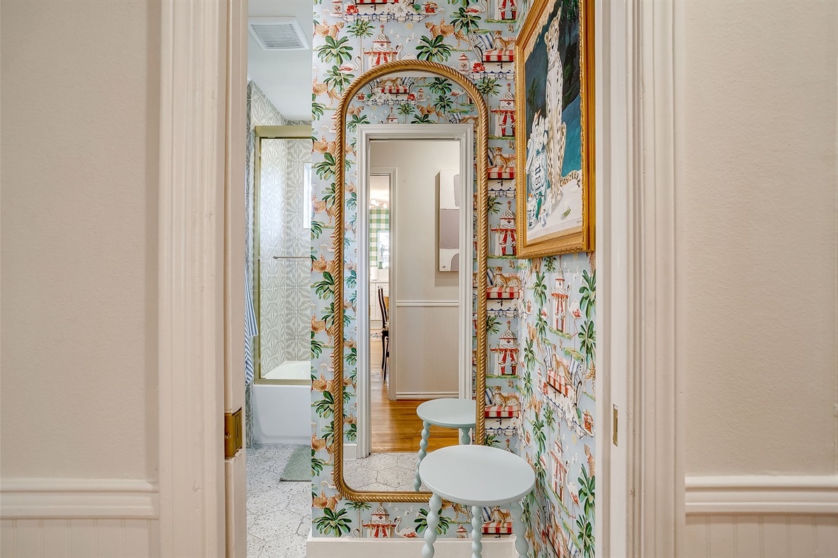 Front hall bath with personality- statement wallpaper, a full-size mirror for final touch-ups, and a styled foyer nook that feels more boutique than basic.