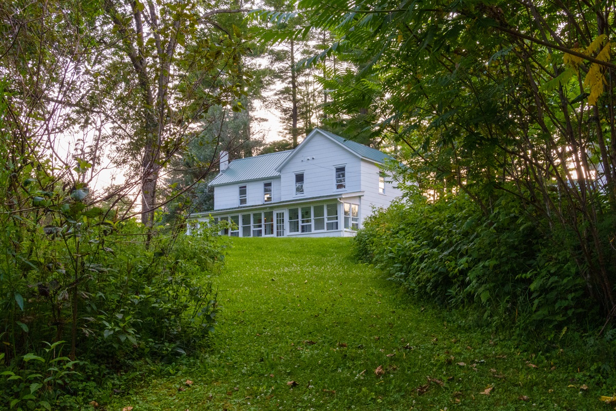 The front of the house from between the trees in the corner. It's a romantic view of the house, which has since had shutters installed.