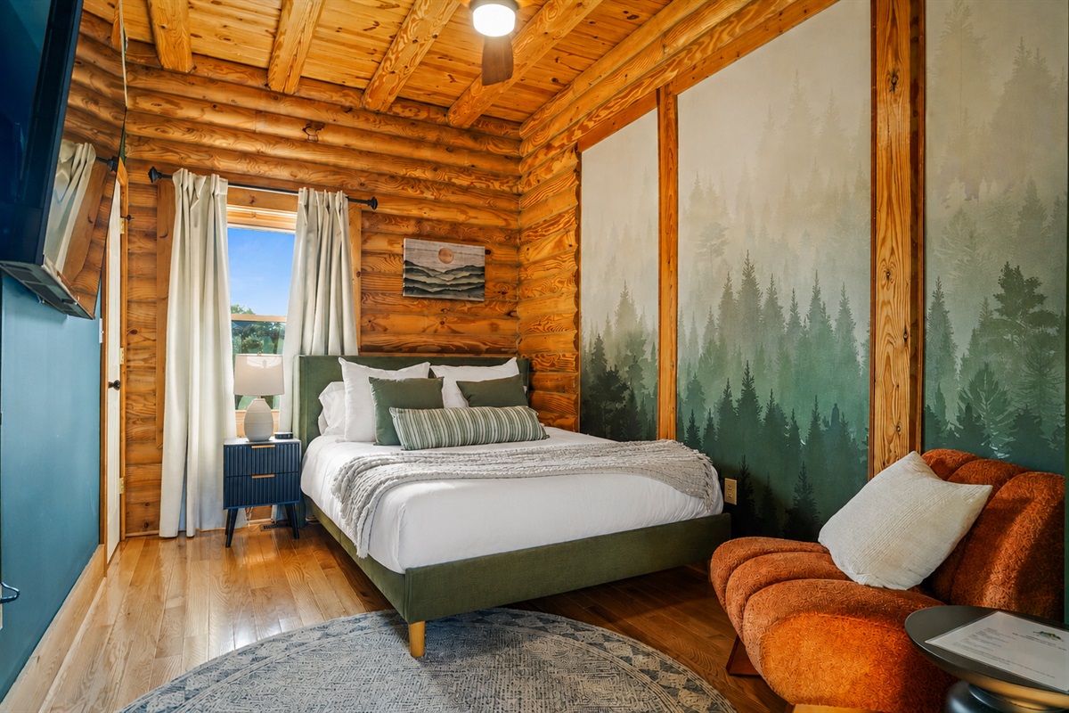 Relax in this beautifully designed guest room featuring queen bed, a nature-inspired accent wall, plush pillows, and a peaceful space to unwind.