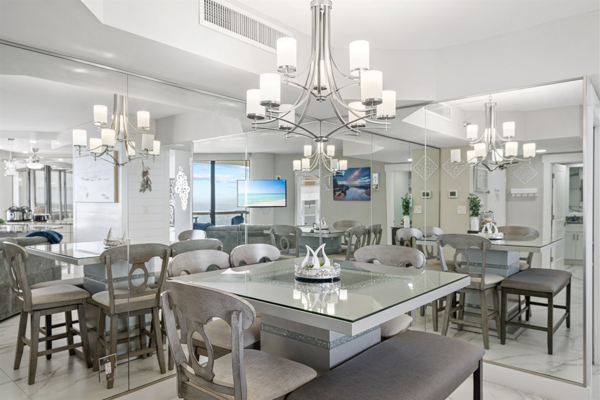 Most vacation rentals have a table and some chairs. This dining room has a statement chandelier, wraparound mirrors, and a glass-top table that makes every meal feel a little more special than it would anywhere else.