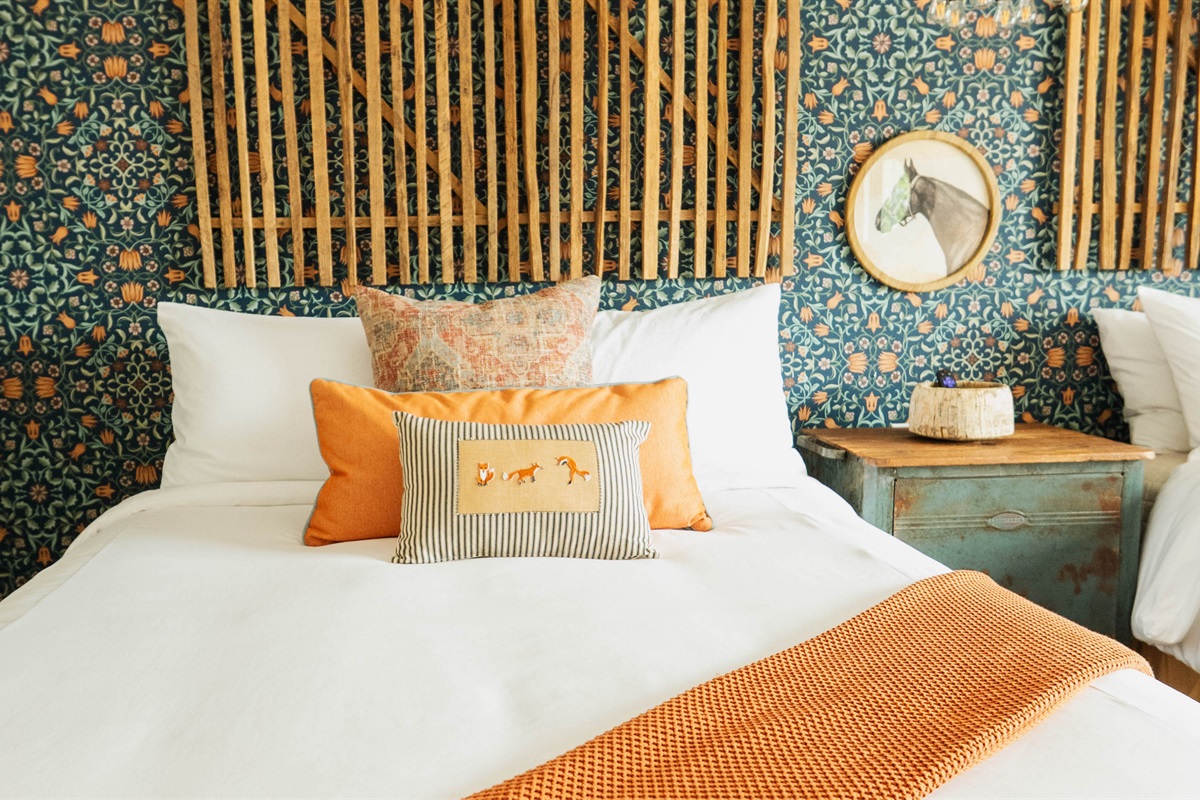 Corral Suite at Gaines Ranch on the Square — a queen bed in premium Comphy linens against a custom modern Western feature wall.