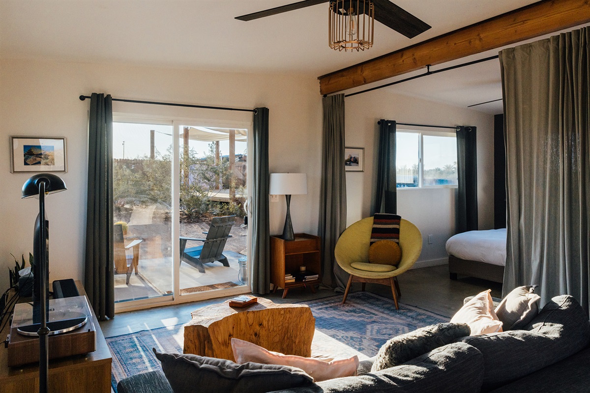 Cozy desert living room with modern seating, stylish decor, and sliding glass doors that open directly to the patio and expansive Joshua Tree views.