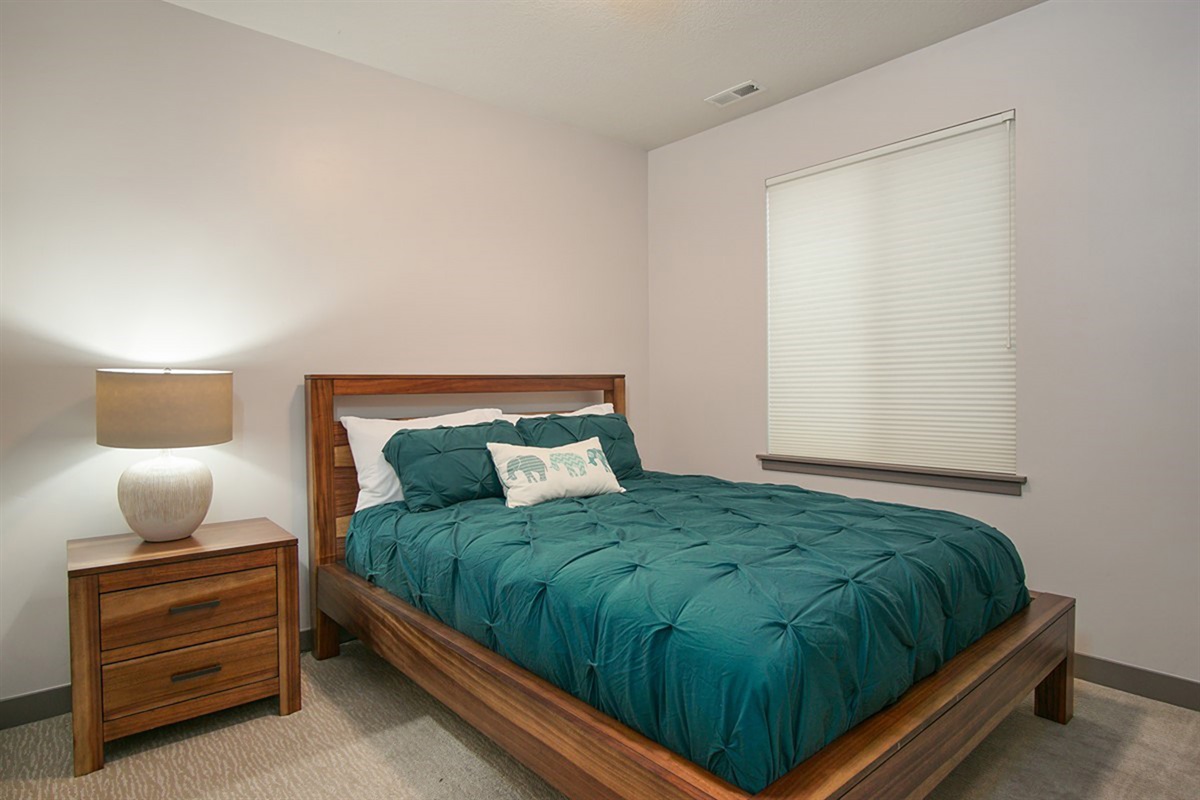 A cozy downstairs queen bedroom offering privacy and comfort, with soft lighting for a restful ambiance - perfect for recharging.