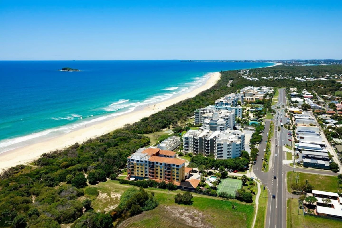 This aerial view shows the coastal setting surrounding Aaron's Beachside Boat House, with Marcoola positioned between the beach, residential streets and local accommodation precinct.