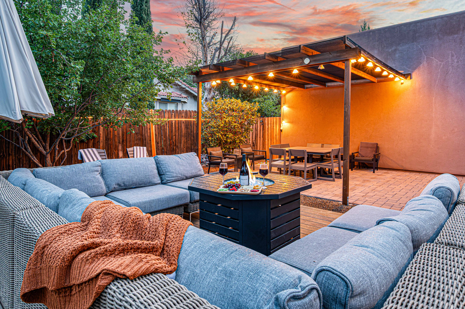 {Outdoor Lounge} Spacious outdoor seating creates an inviting place for the whole group to gather beneath the pergola and string lights.