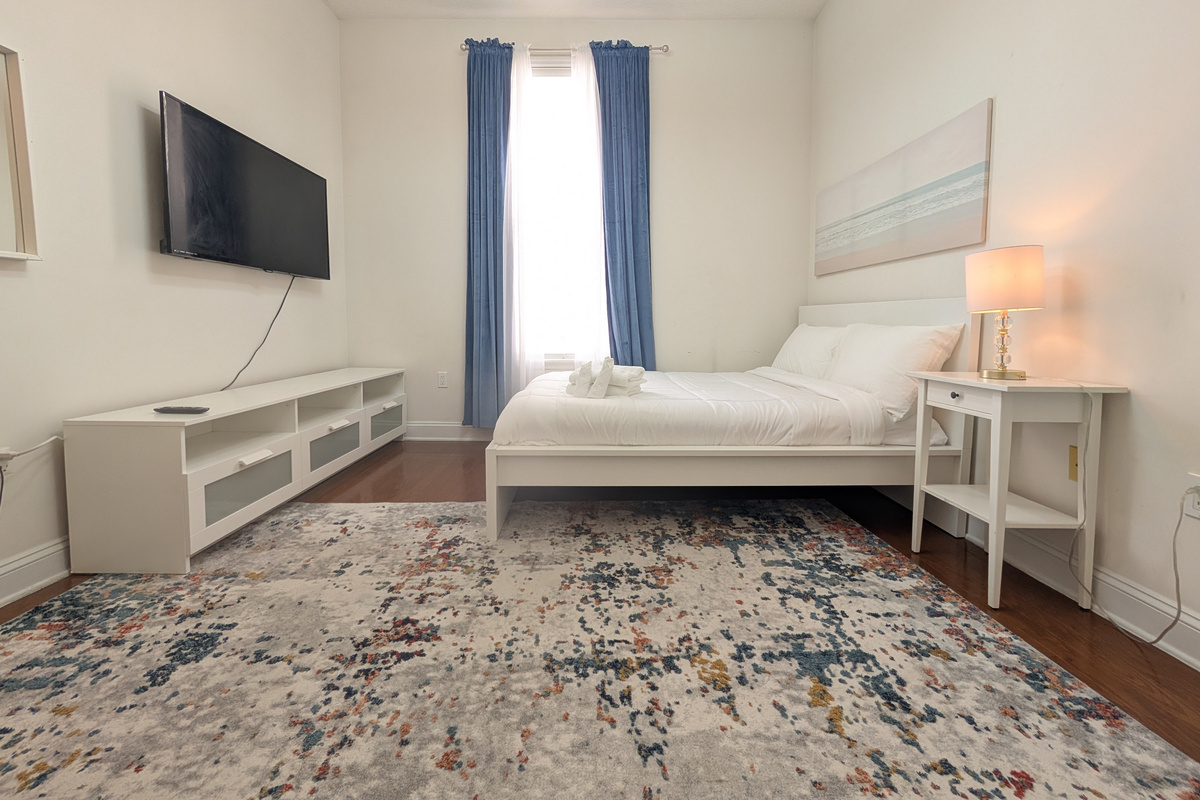 Comfortable guest bedroom with a TV, soft bedding, and plenty of space to settle in.
