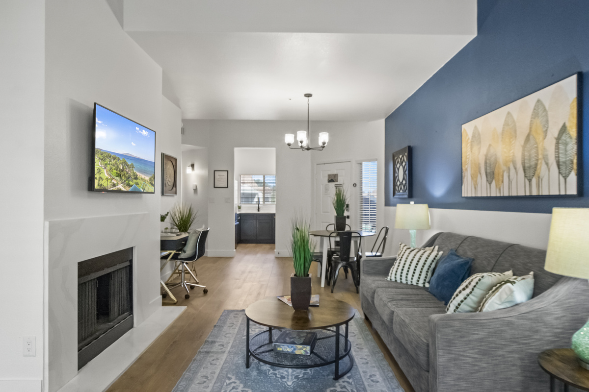 Spacious living room with a Roku smart TV, work desk, a fire place and a snug couch for added comfort. 