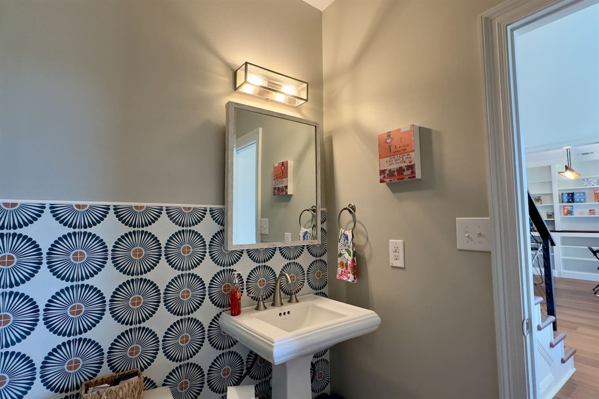 A pedestal sink with chrome fixtures and a rectangular mirror keeps the space sleek and functional.