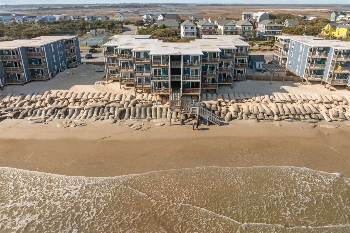 Wide aerial perspective showing the beachfront buildings and surrounding coastal neighborhood