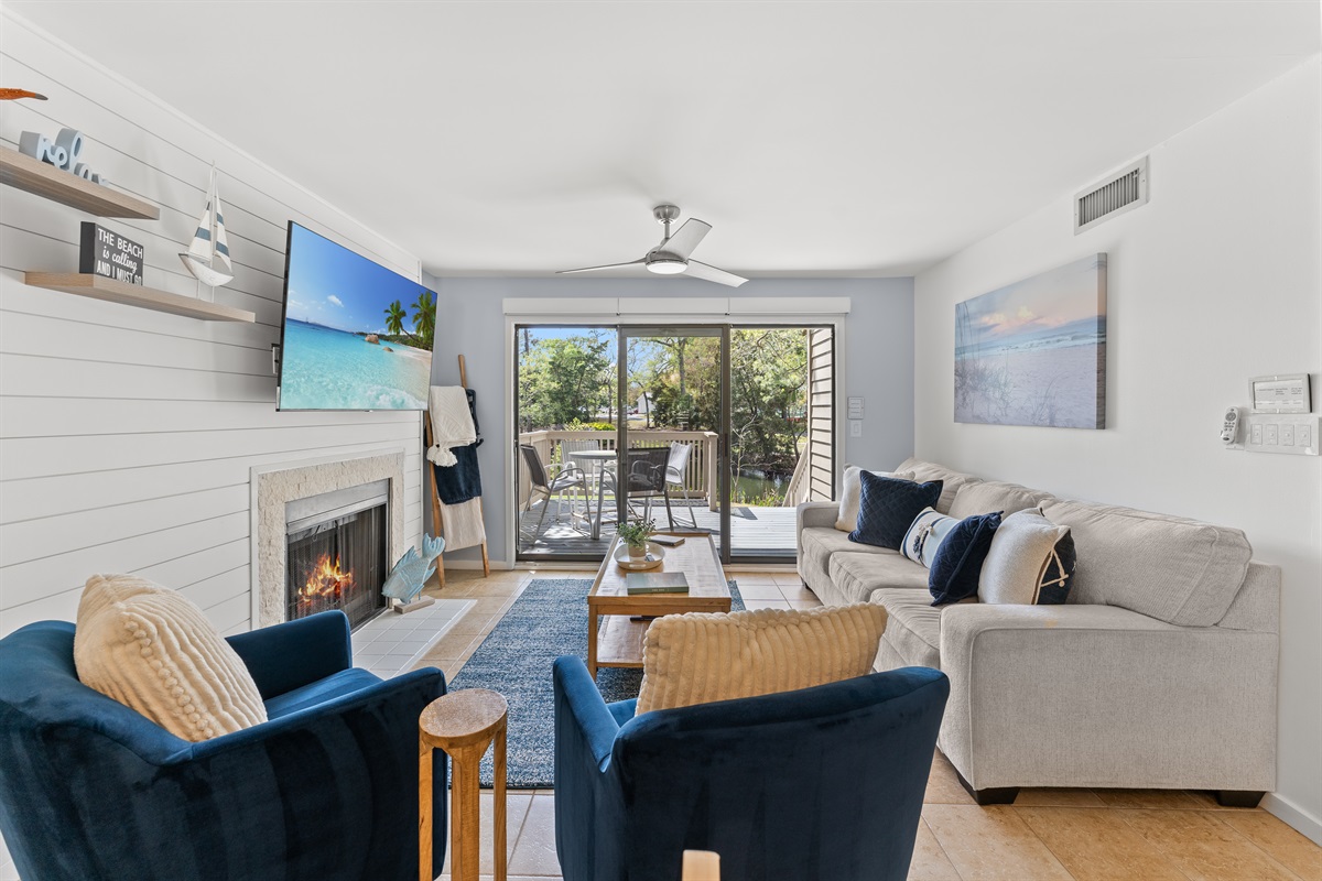 Spacious open Living room with fireplace, large TV and deck access.