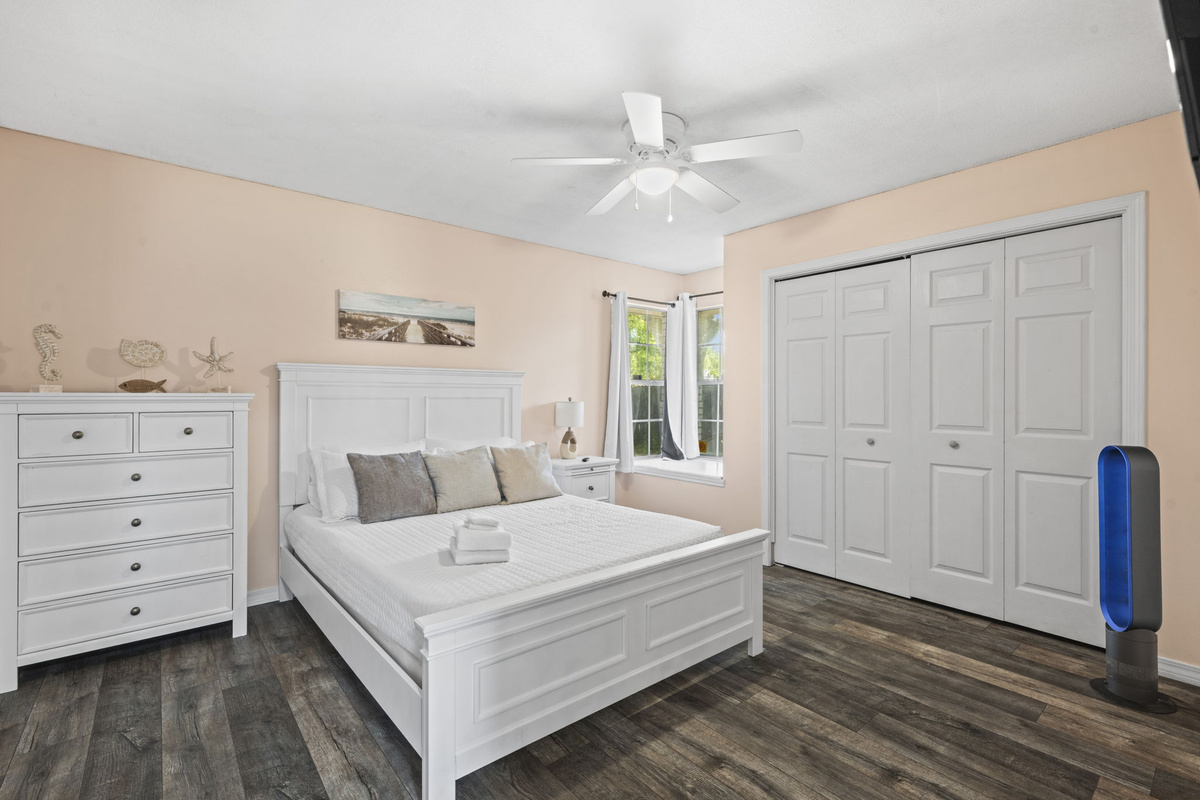 A soft, sunny bedroom with a plush white bed, dresser, and closet space for extended stays.