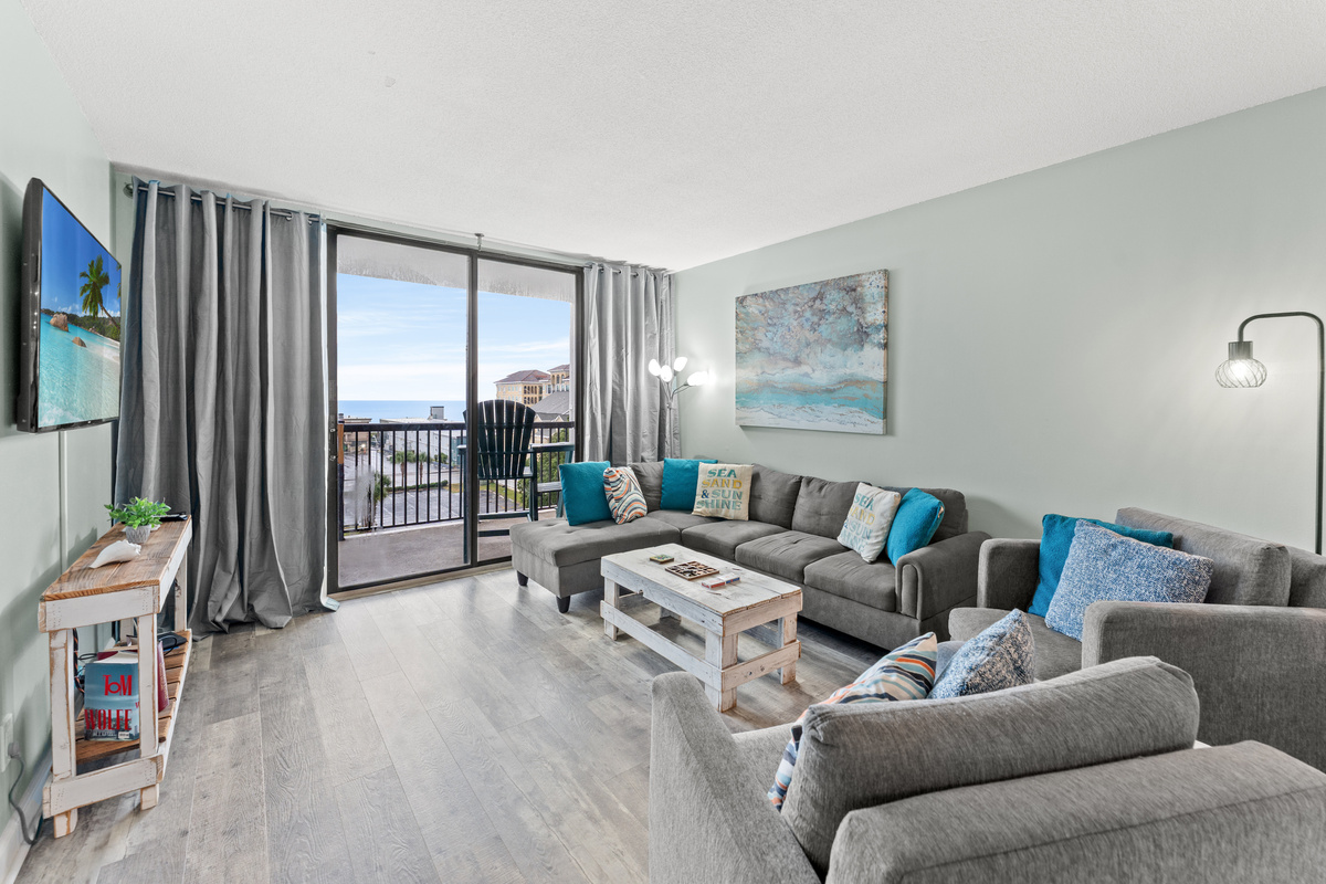 Comfy living room area with large TV and balcony access