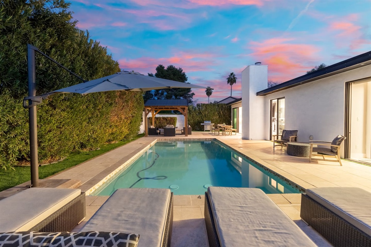 Lounge in luxury as the sunset reflects over the pool—perfect for a serene evening with a backdrop of lush greenery.