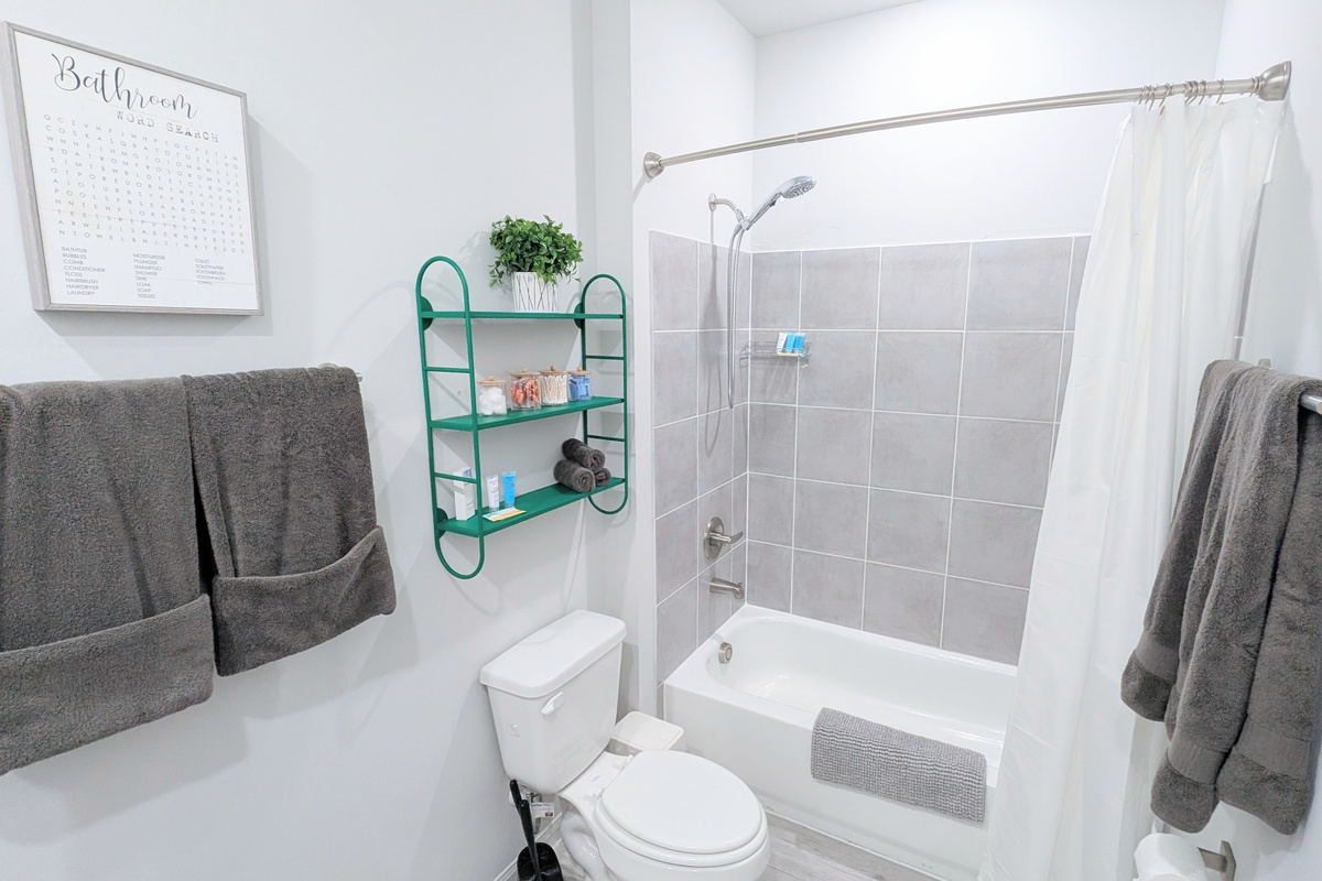 En suite bathroom located off the primary bedroom is fully stocked with fluffy towels, basic toiletries, and all the comforts of home. 