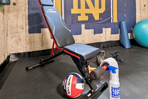 Fuel your fitness with Fighting Irish pride—our South Bend guest retreat gym features a bold ND sign, workout bench, weights, and gear to keep your crew moving near Notre Dame.