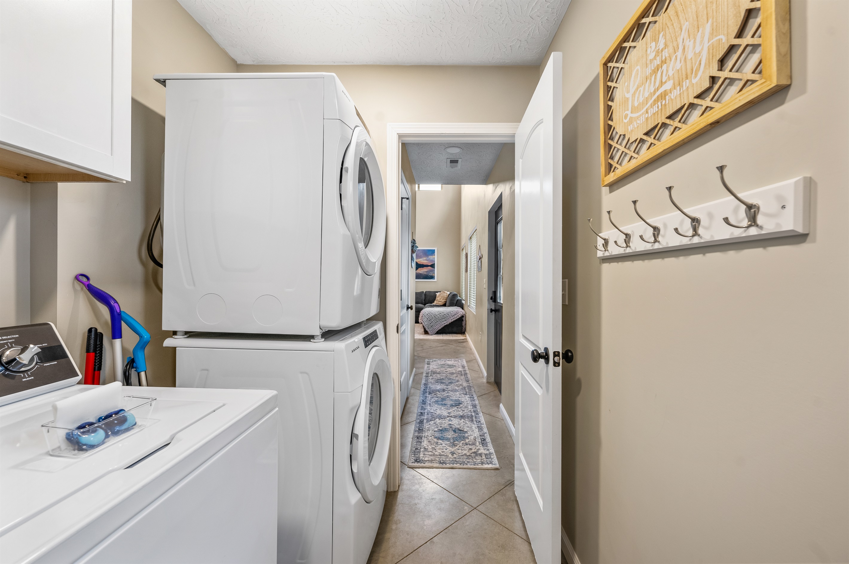 Located down the hall from the living room, the first-floor laundry room includes a Speed Queen washer, two dryers, a starter pack of laundry pods and dryer sheets, a broom/dustpan, Swiffer, and small sweeper.