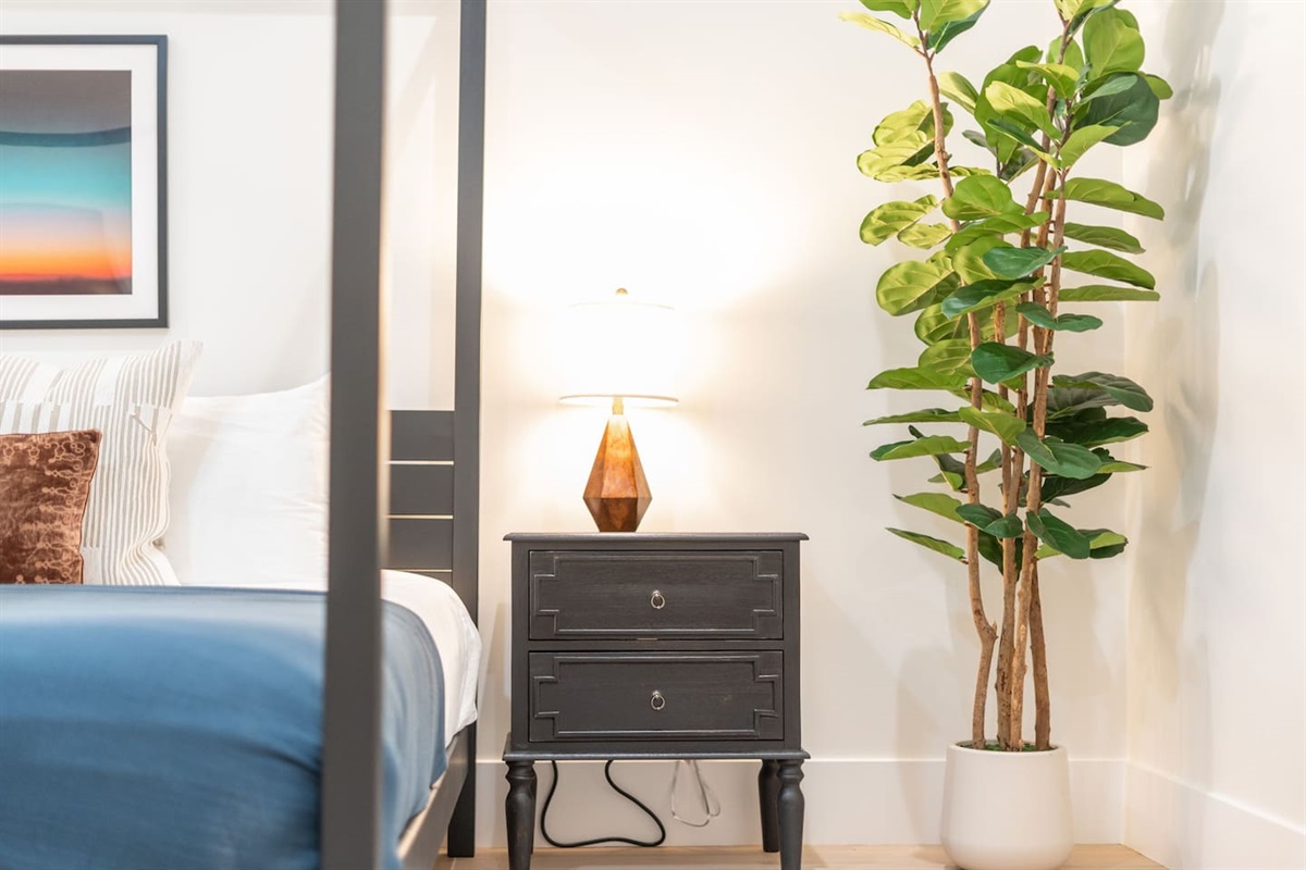 Bright and inviting nightstand setup with geometric lamp and lush greenery for a cozy touch.