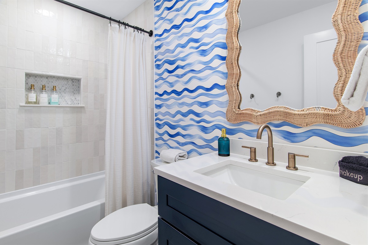A fun, coastal-inspired bathroom with a tub/shower combo and charming wave details.