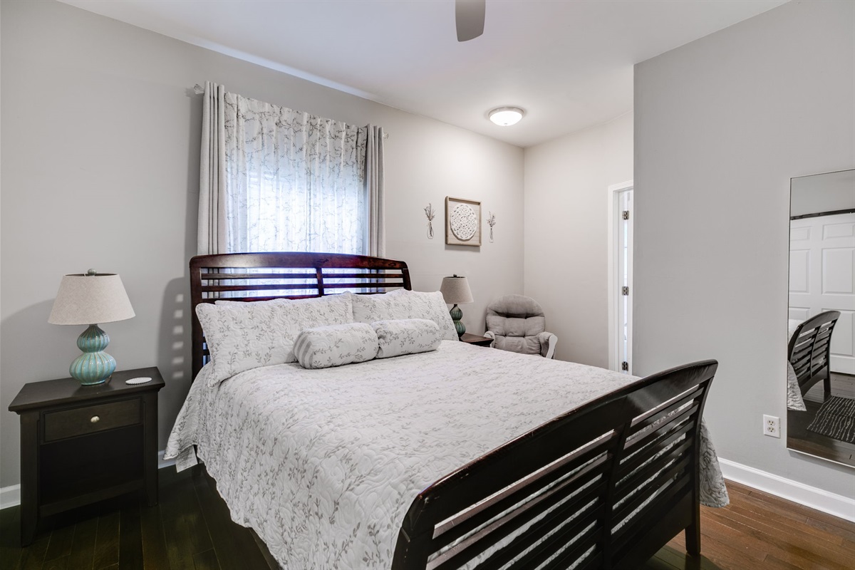 Your downstairs retreat: spacious queen, stylish gray-leaf bedding, hardwood floors, big closet, rocking chair, and shared Jack & Jill bath.