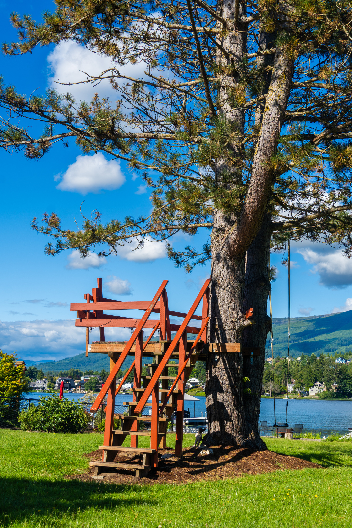 A bird-watching tower rises above a backyard that flows straight into the lake, with open views across the water and distant shoreline.