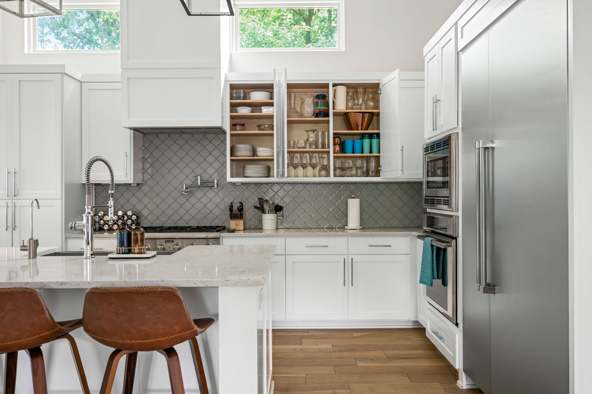 Well-appointed kitchen corner with a prep sink, open shelving, and pantry storage — functional design meets modern style.
