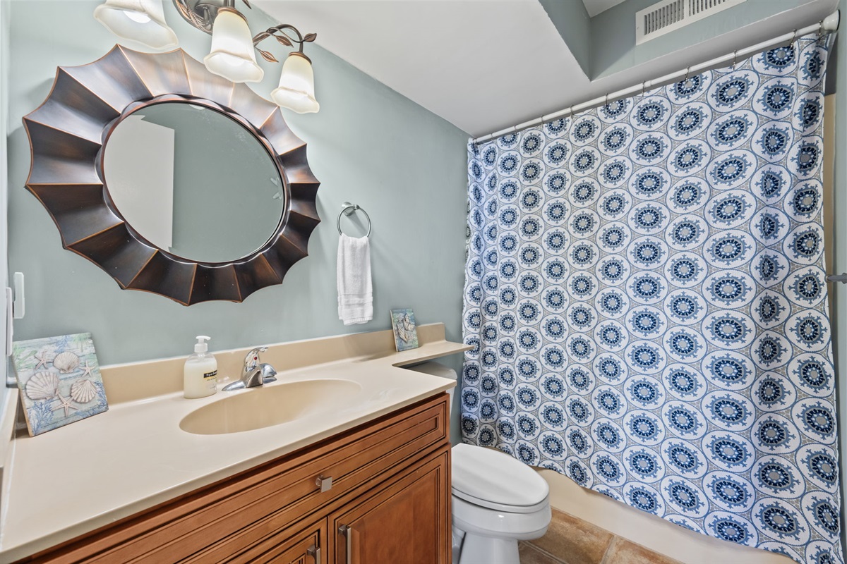 Full hallway bathroom featuring a tub/shower combo, fresh linens, and a bright, beach-inspired design