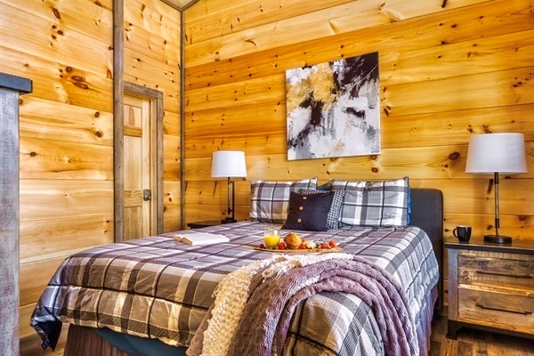 Spacious master suite conveniently located on the first floor, just steps from the cozy living room—complete with plush bedding, rustic decor, and warm natural light.