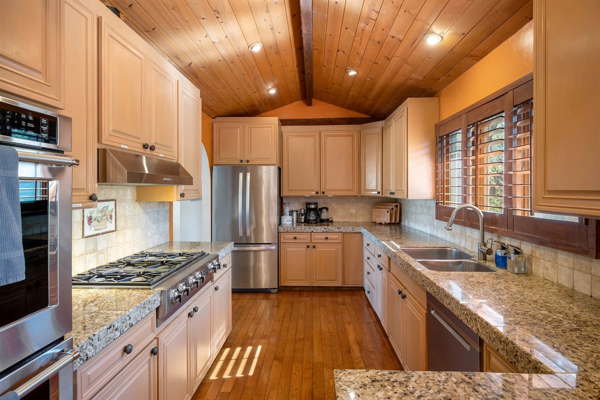 Ample kitchen space, equipped with double ovens, 6-burner gas stove, large refrigerator, and a standard set of cooking equipment.