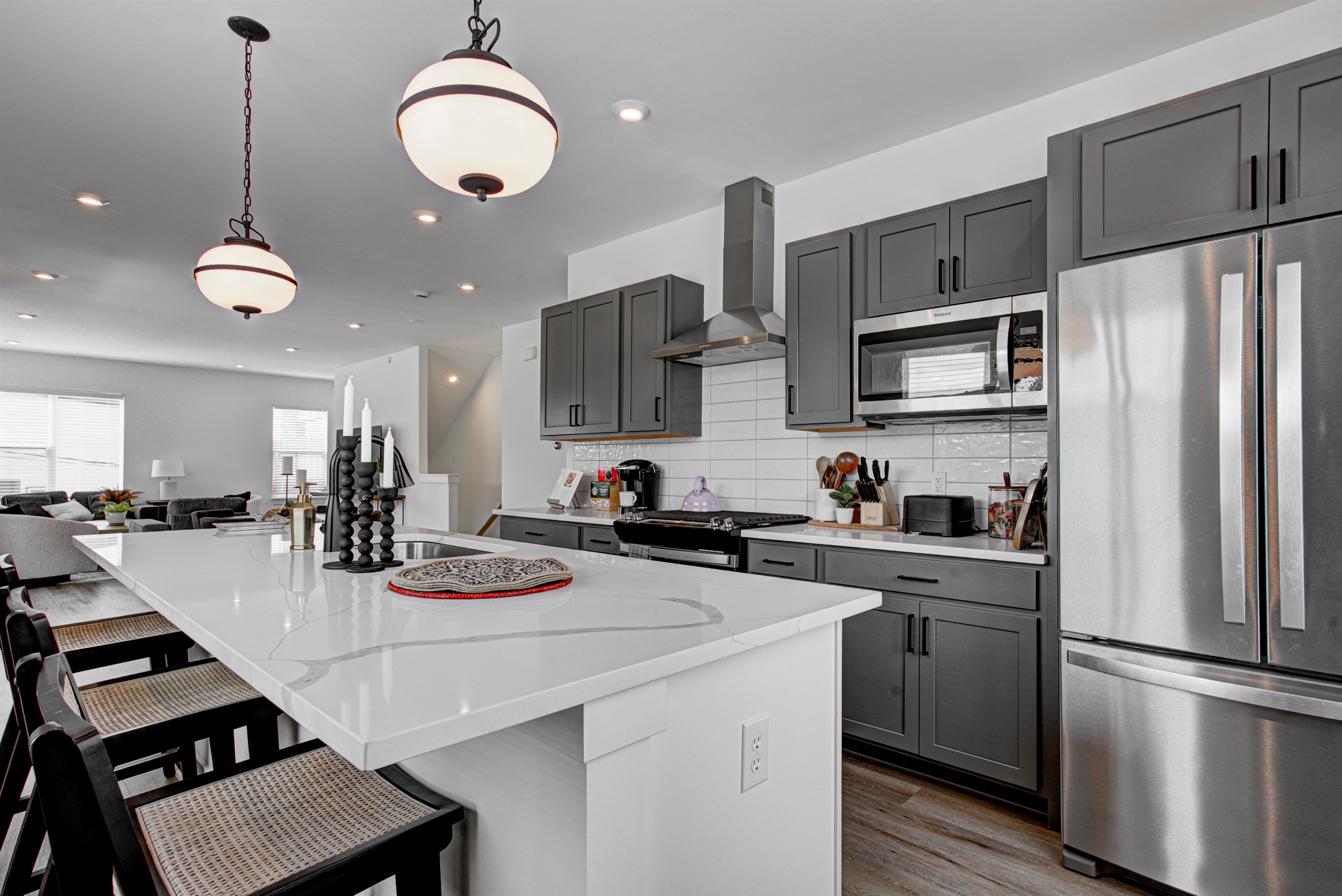 Enjoy a designed open-concept space with a modern kitchen equipped with quartz countertops, stainless steel appliances, and all essentials for home cooking. 