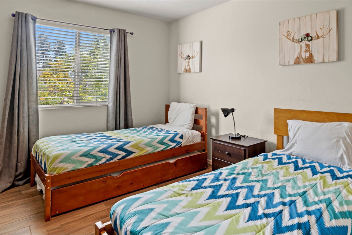 Cozy third bedroom featuring two twin beds, providing a comfortable space for restful nights, with easy access to the adjoining hallway.
