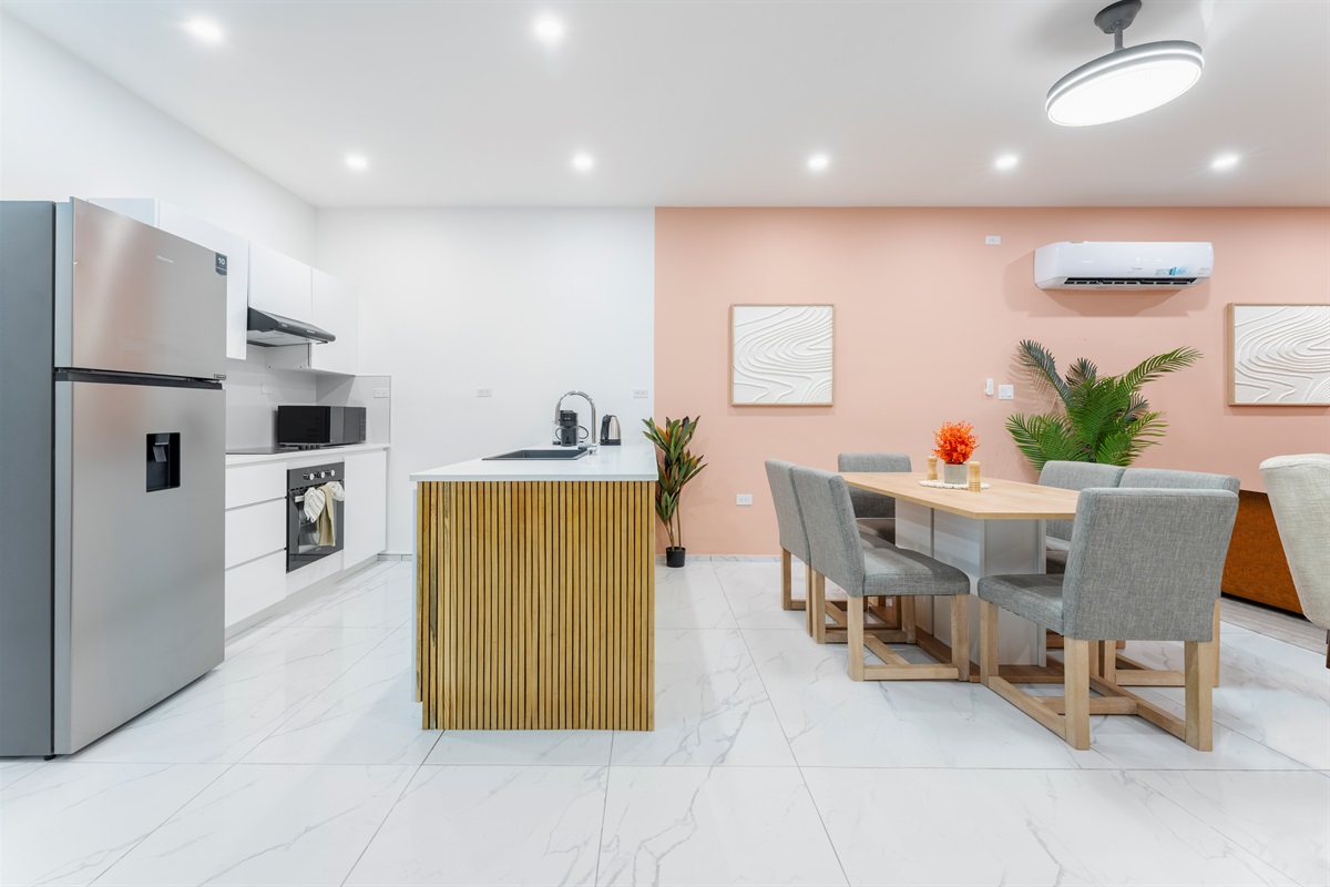 Modern chef’s kitchen with stainless appliances, full dining table and warm wood finishes.