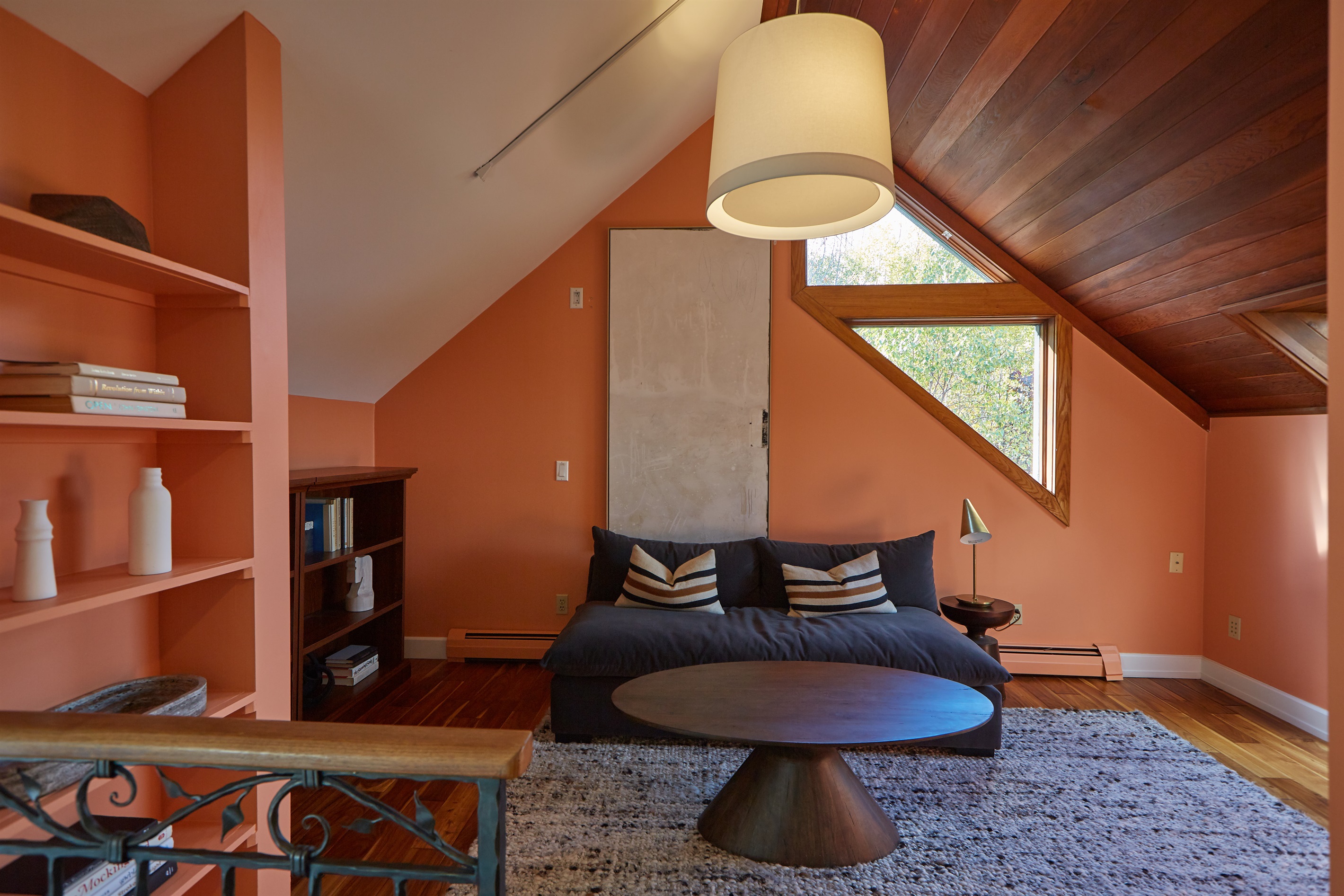 Unwind in this cozy, uniquely designed library room on the second floor featuring warm tones, a cozy reading area, and vaulted ceilings.
