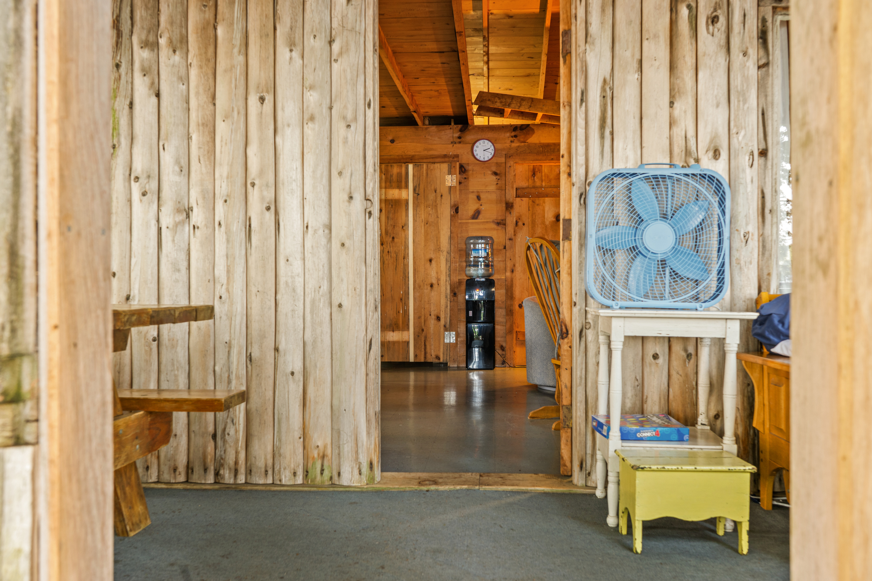 Straight-through view at Loonrise Point! Looking in from outside, through the screened porch & living space all the way to the Primo water dispenser. Demonstrates our open-concept layout & rustic log-slab walls on Beech Hill Pond in Otis, ME.